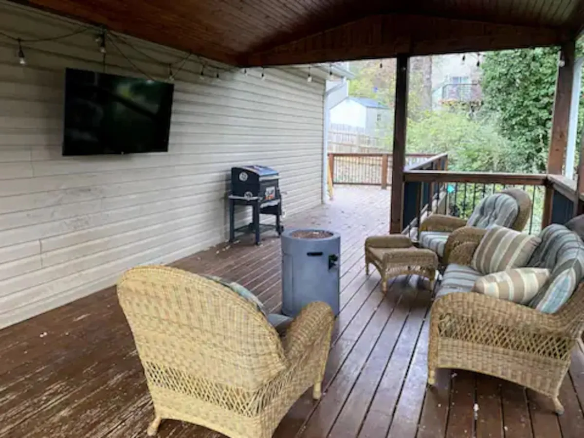A comfortable outdoor seating area with wicker chairs, a grill, and a television—ideal for group barbecues and outdoor entertainment.