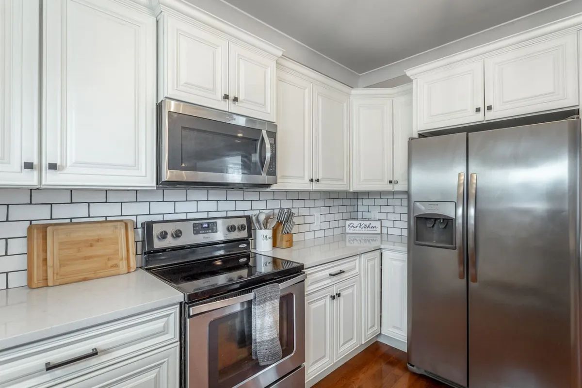 This image features a modern kitchen with stainless steel appliances, white cabinetry, and a stylish subway tile backsplash. The spacious countertops provide ample room for cooking and meal prep, while the overall design exudes a welcoming, family-friendly atmosphere.