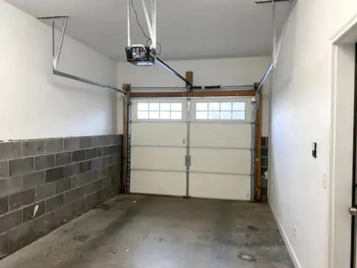 A practical garage space with a visible garage door, concrete floor, and storage area—demonstrating abundant space for vehicle parking and easy loading/unloading between adventures.