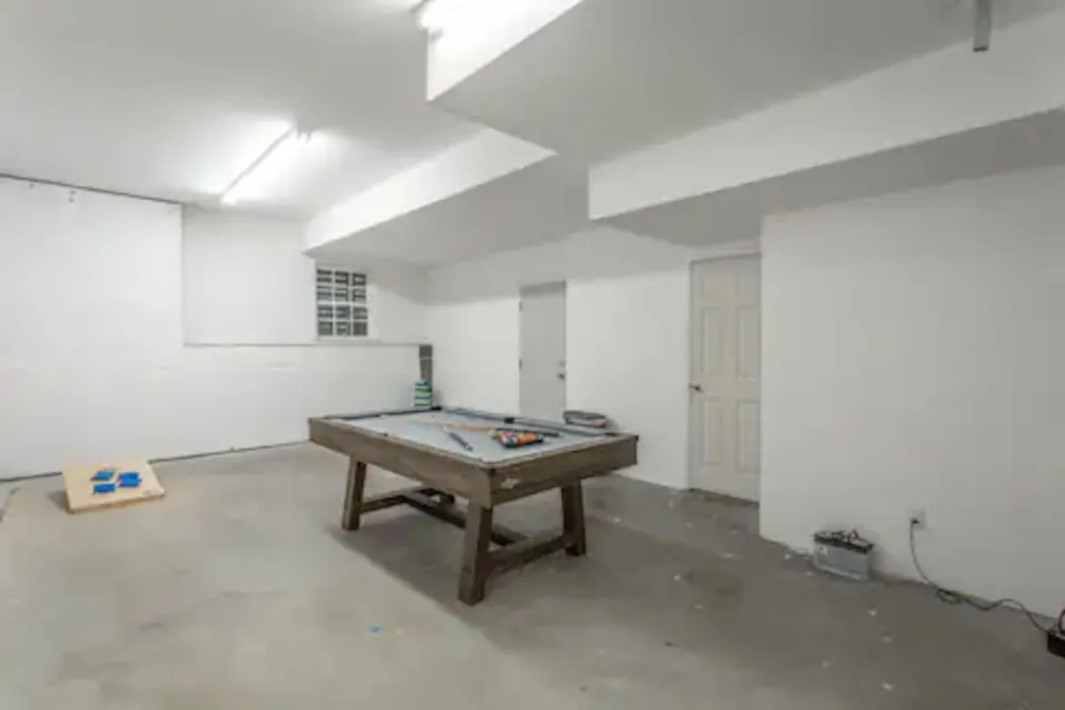 This interior shot spotlights a pool table in a bright, welcoming game room, with white walls and a visible doorway. The space is set up for social interaction and friendly competition, reinforcing the entertainment focus of the section.